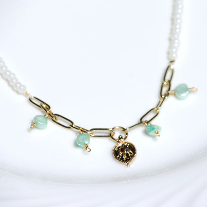 Close up of blue lagoon necklace, featuring paperclip chain, freshwater pearls, and elephant charm. 