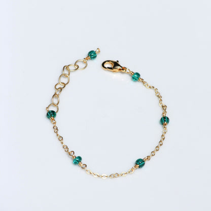 Photo of handmade dainty bracelet, featuring gold plated chain and teal seed beads.