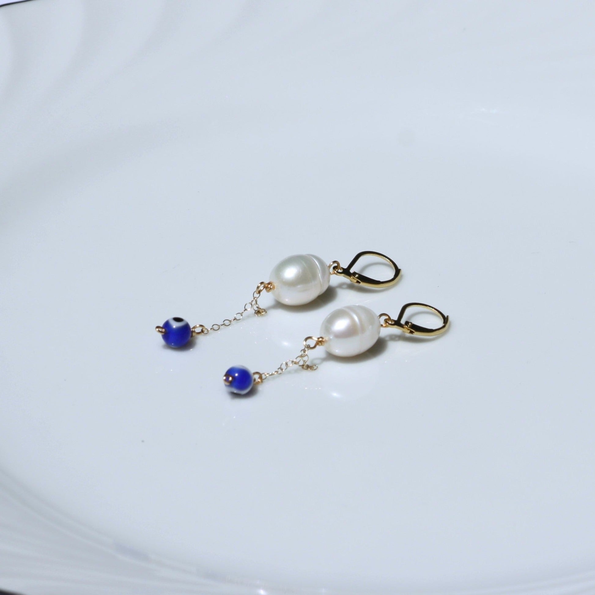 Pearl dangle earrings with evil eye bead.