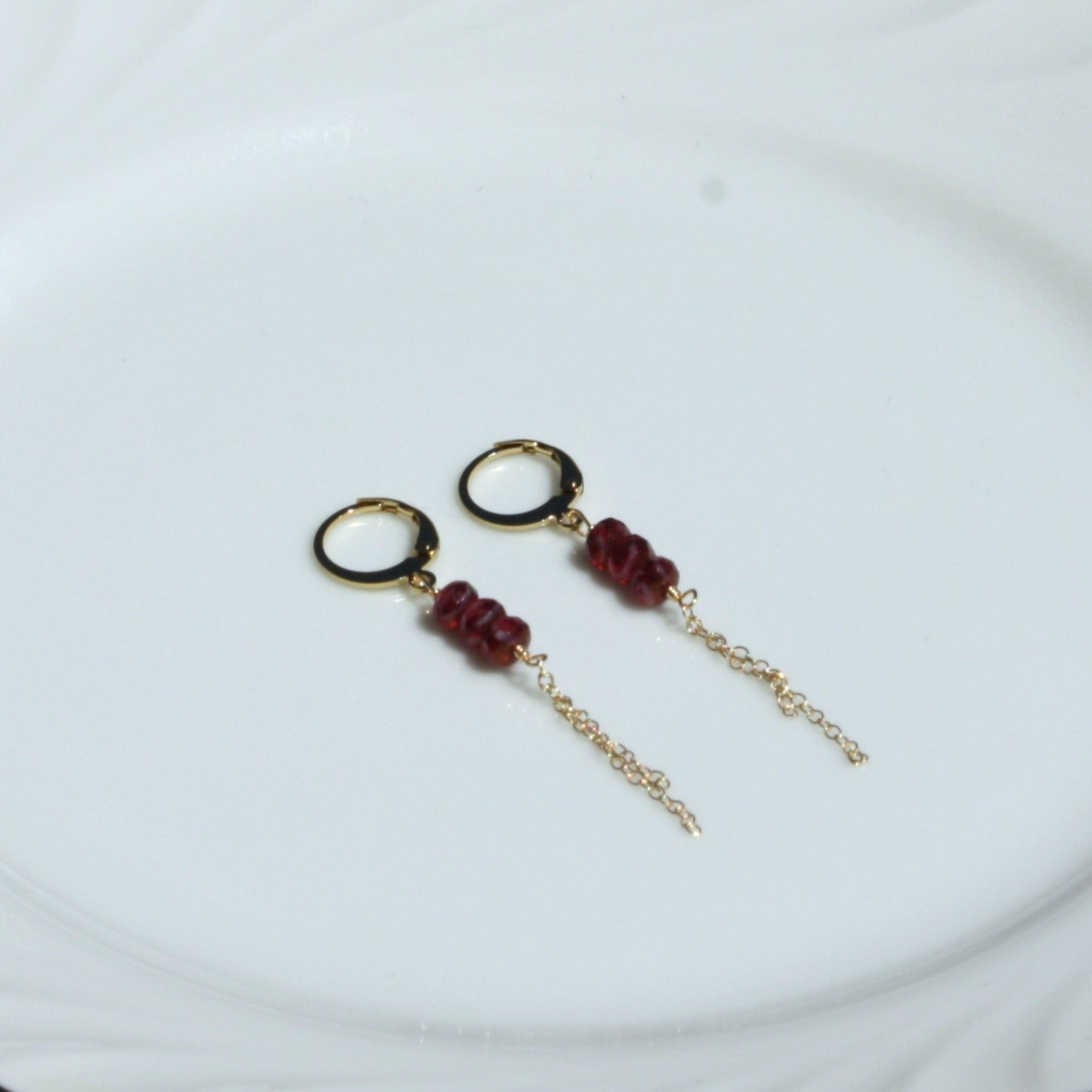 Photo of pastel huggie earrings in ruby.