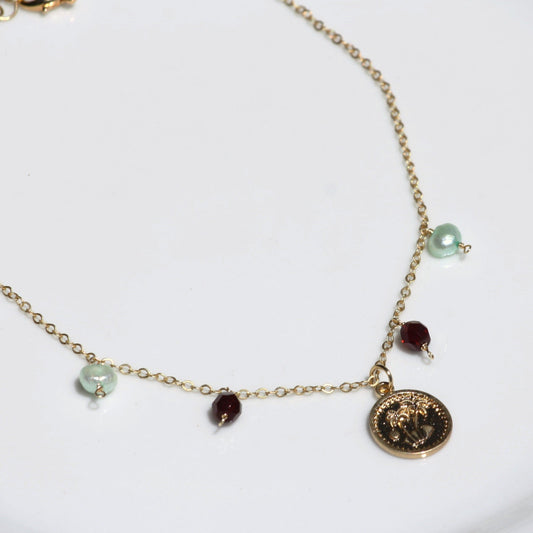 Necklace with charm featuring pearls and garnet beads.