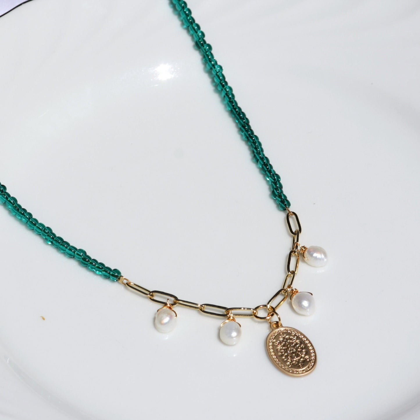 Green beaded necklace with white pearls and gold charm.